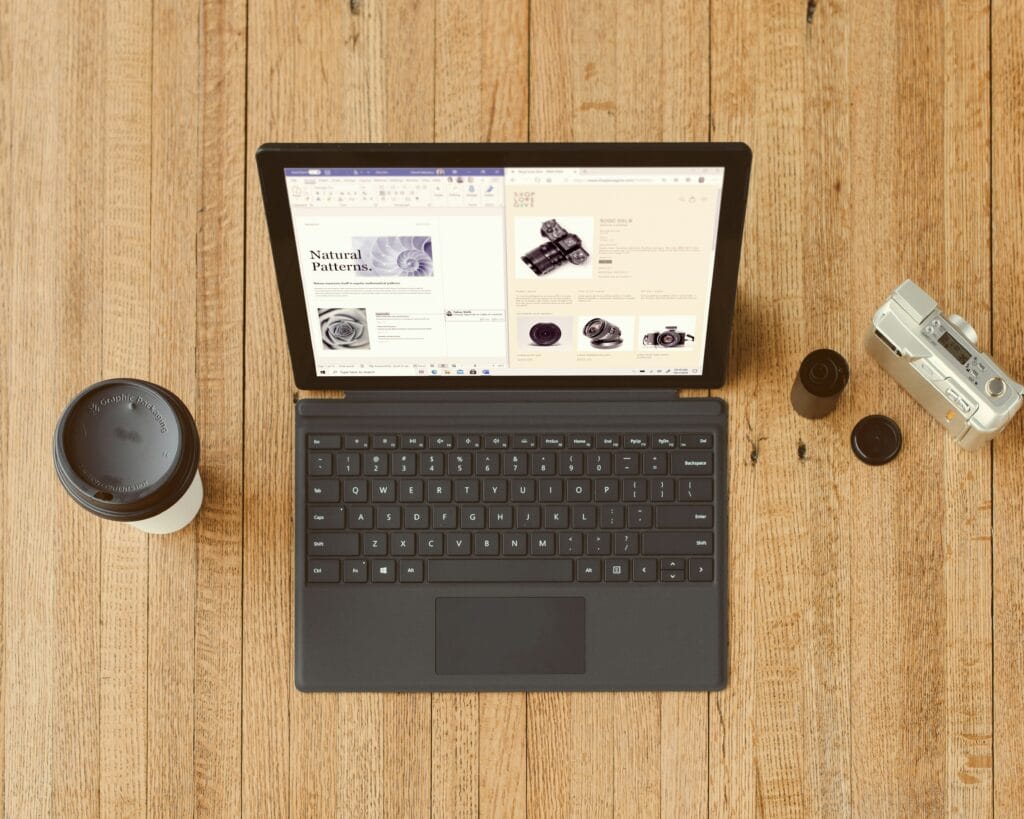 Flat lay of laptop, vintage camera, coffee cup, and film rolls on wood background — tech lifestyle for modern smart shoppers.