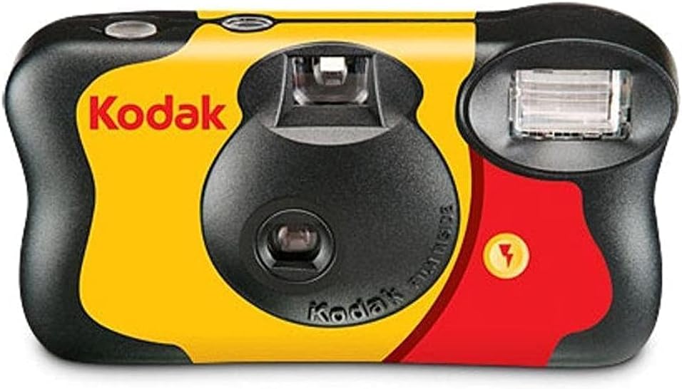 Camera disposable Kodak on a desk beside developed photos and film roll – classic single-use film camera for effortless photography