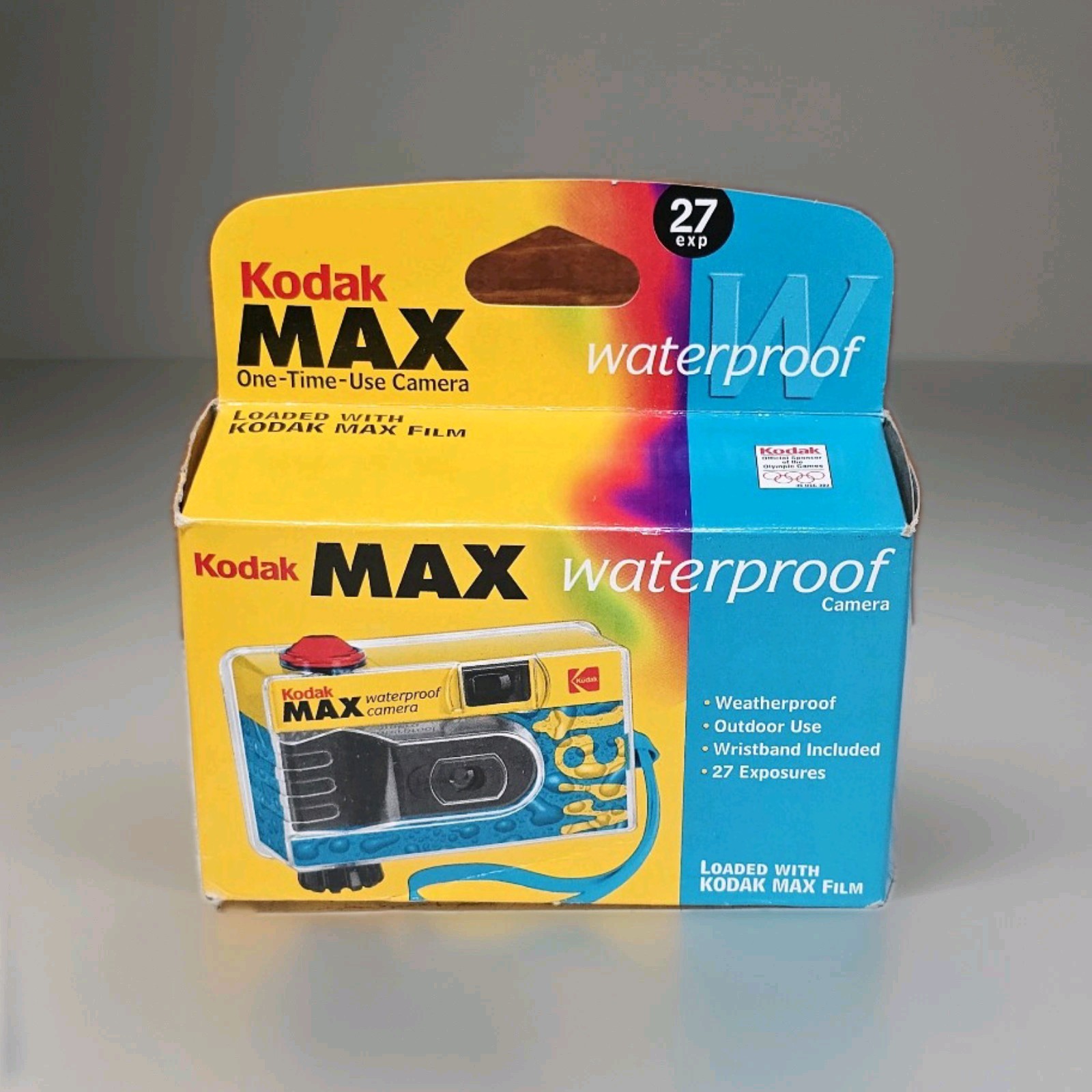 Disposable Kodak camera on a wooden table beside film roll and printed photos – single-use film camera for nostalgic photography lovers